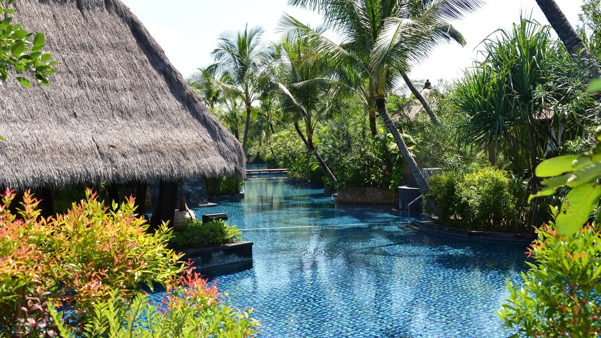 Infinity pool with thatched pavilion and tropical gardens, Bali, Indonesia