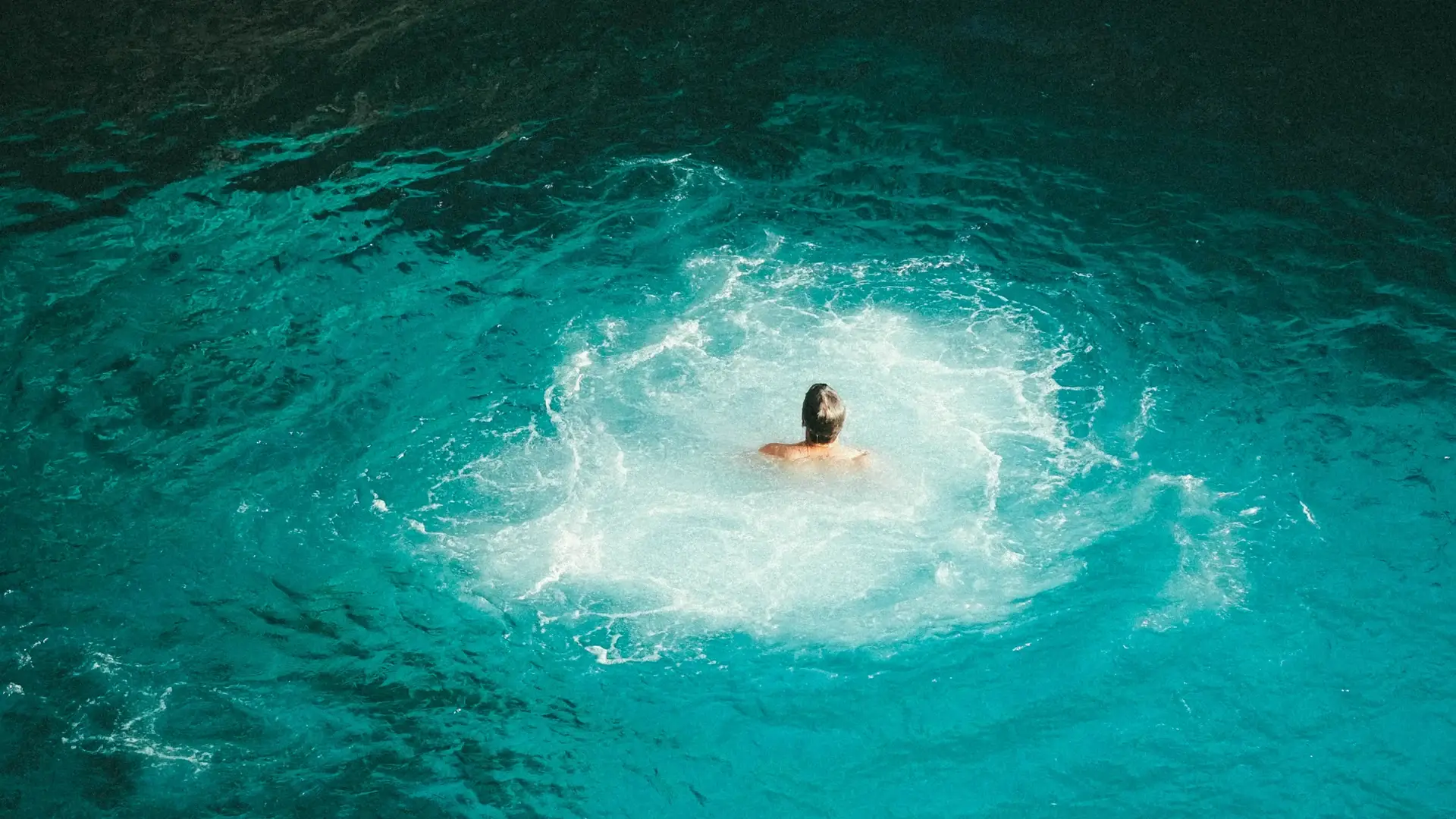 Swimmer jumping into turquoise Caribbean Sea at Rick's Cafe, Negril, Jamaica